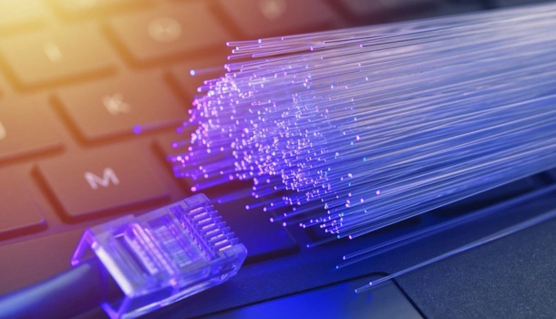 A glowing fiber optic cable and an Ethernet connector rest on a laptop keyboard