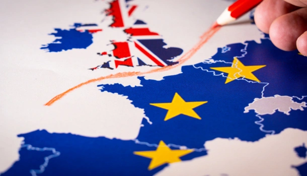 A hand drawing a red line between the United Kingdom and mainland Europe on a map overlaid with the Union Jack and EU flag