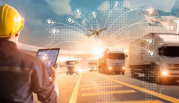 Logistics manager using a tablet to monitor a fleet of connected trucks on a highway with digital tracking icons overlayed