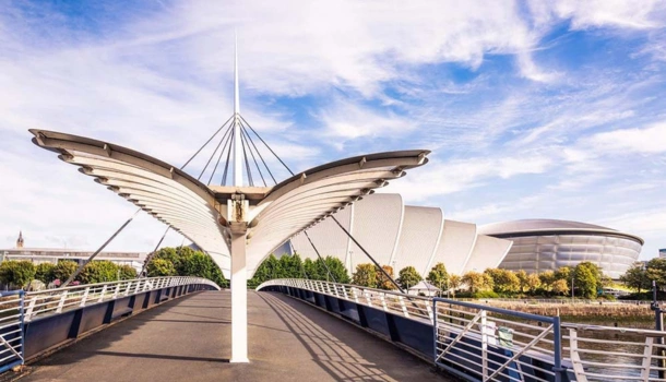 A modern pedestrian bridge leading toward the SEC Armadillo and OVO Hydro buildings in Glasgow