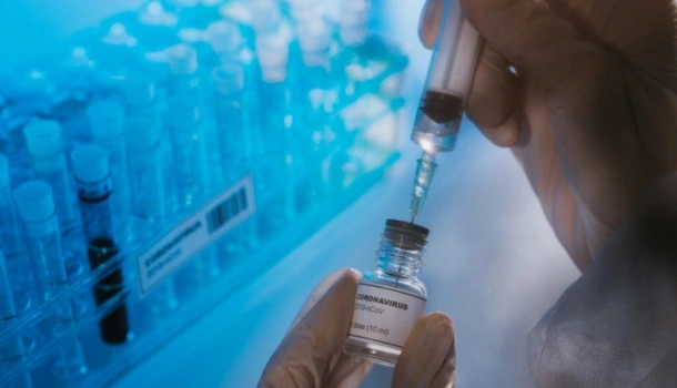 Close-up of a gloved hand drawing a dose from a COVID-19 vaccine vial