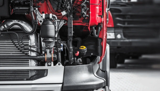 Close-up of a truck with its hood open, revealing the engine and mechanical components