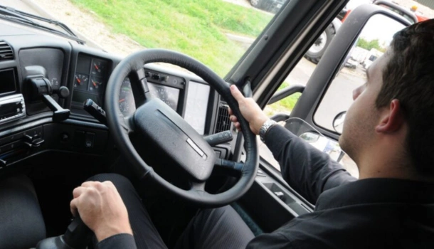 A man in a black shirt driving an HGV