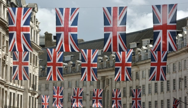 Rows of Union Jack flags hang across a street lined with historic buildings