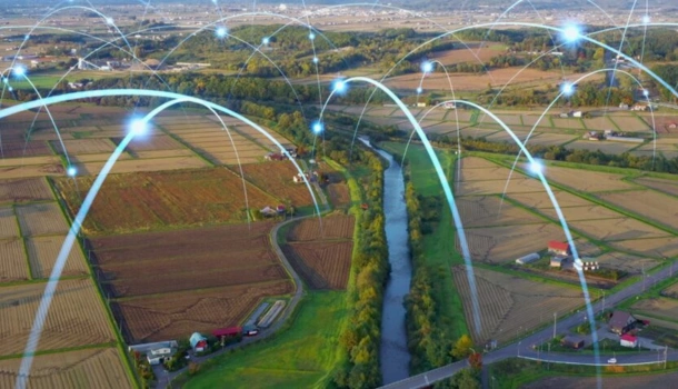 Aerial view of a rural landscape with digital arcs and glowing connection points over fields and roads