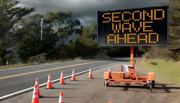 A roadside electronic sign reads "SECOND WAVE AHEAD" surrounded by traffic cones