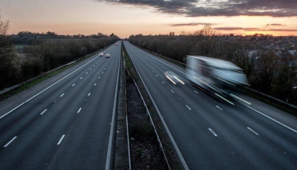 Nearly empty dual carriageway at dusk with a blurred truck speeding down one side