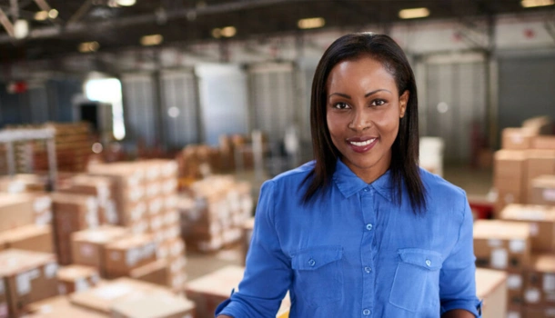 A confident logistics manager standing in a warehouse filled with boxes