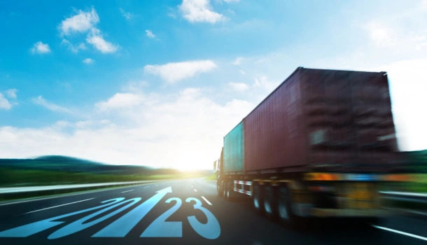 A cargo truck speeds down a highway with "2023" marked on the road