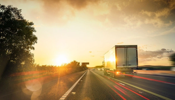 A large HGV truck driving down a highway at sunset
