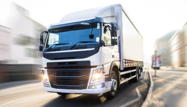 White lorry driving at speed through a city street during daylight