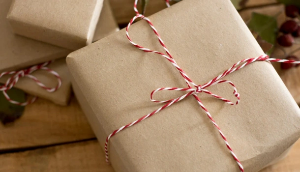Brown paper packages tied with red and white string sit on a wooden surface