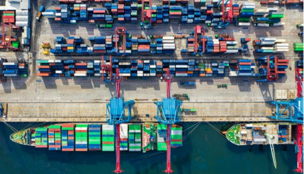 Aerial view of a busy shipping port with colorful cargo containers, cranes, and container ships