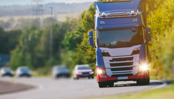 A brightly colored blue and red semi-truck drives along a country road during daylight