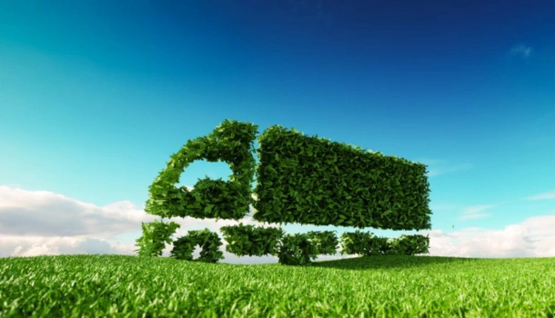 Eco-friendly truck shape made of green foliage on a grassy field under a blue sky
