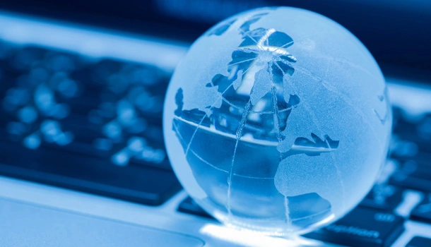 A translucent glass globe rests on a laptop keyboard