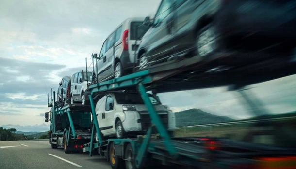 A car transporter truck drives down a highway carrying multiple vehicles on its trailer